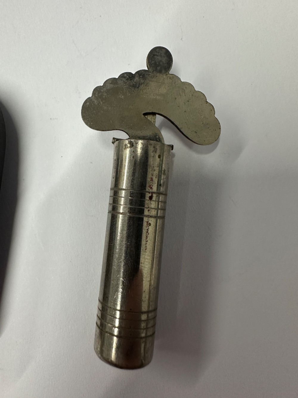 A cylindrical nickel-plated chromatic variable pitch pipe with a note scale arc sitting inside its open red metal case. View VI