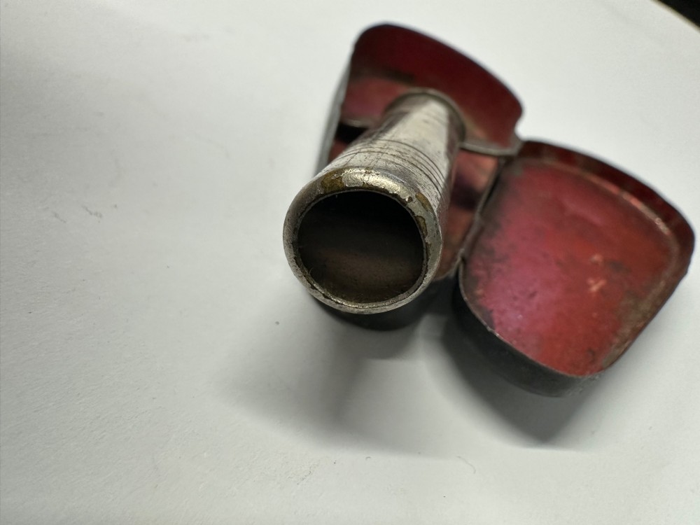 A cylindrical nickel-plated chromatic variable pitch pipe with a note scale arc sitting inside its open red metal case. View XI