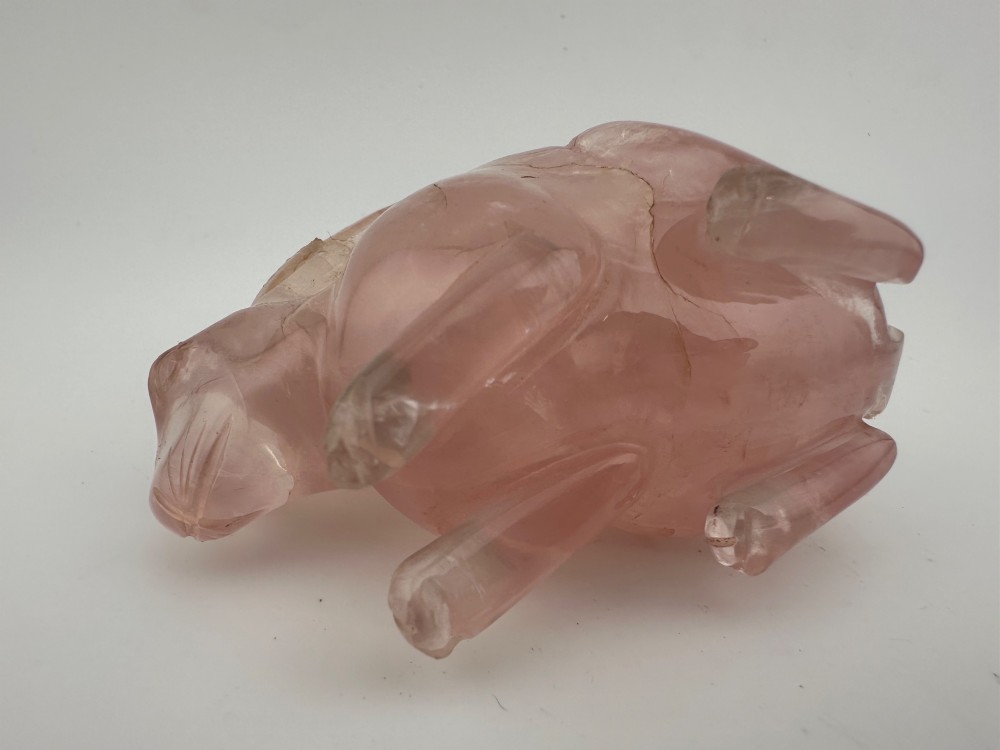 A hand-carved pink rose quartz rabbit figurine with upright ears seated on a dark fitted hardwood display base. View VI