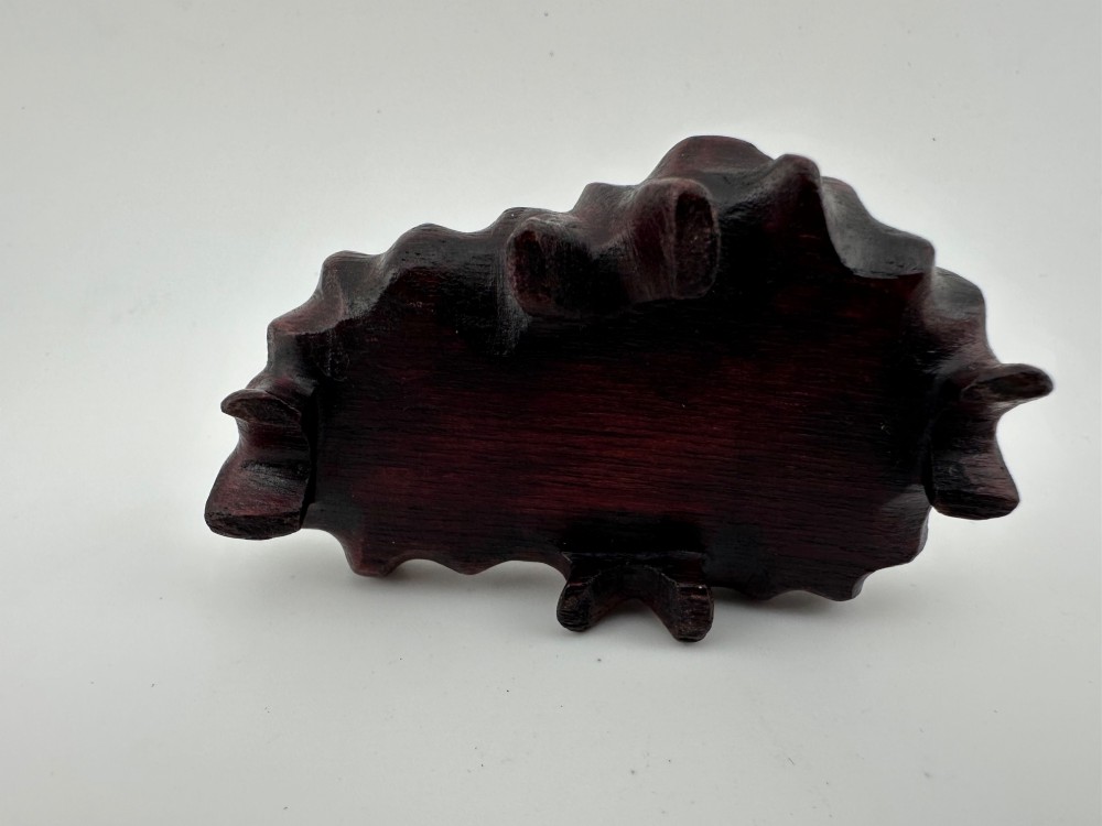 A hand-carved pink rose quartz rabbit figurine with upright ears seated on a dark fitted hardwood display base. View IX