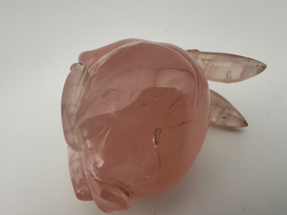 A hand-carved pink rose quartz rabbit figurine with upright ears seated on a dark fitted hardwood display base. View XI