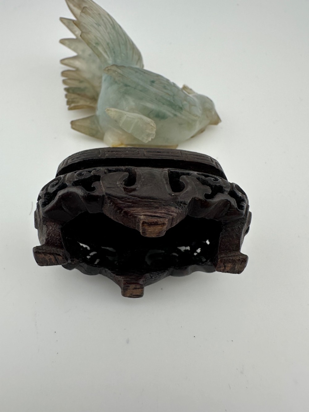 A hand-carved pale green jade sculpture of a cockerel with fan-shaped tail feathers, displayed on a dark carved hardwood base. View XI