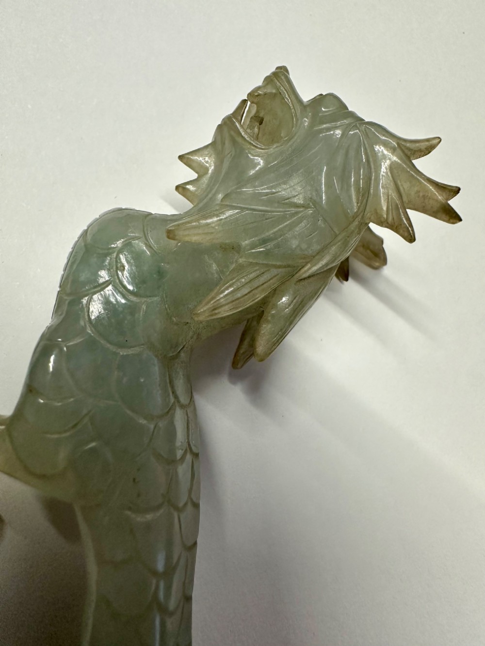A carved pale green jade dragon sculpture shown alongside a dark pierced hardwood display stand. View III