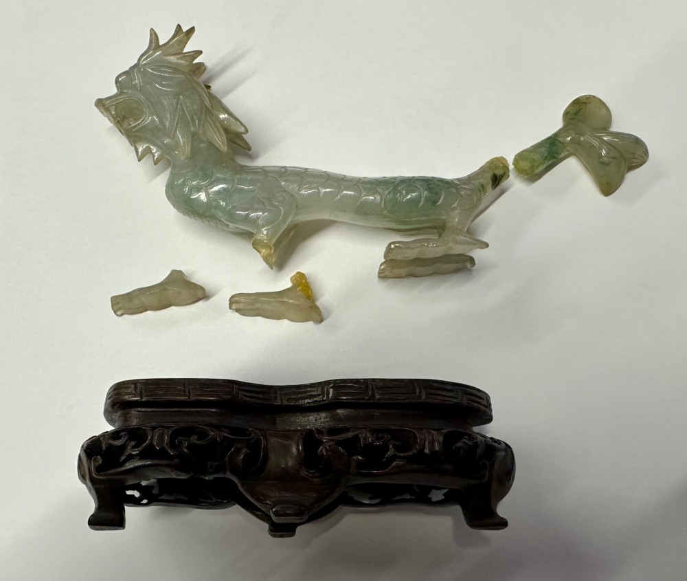 A carved pale green jade dragon sculpture shown alongside a dark pierced hardwood display stand. View V