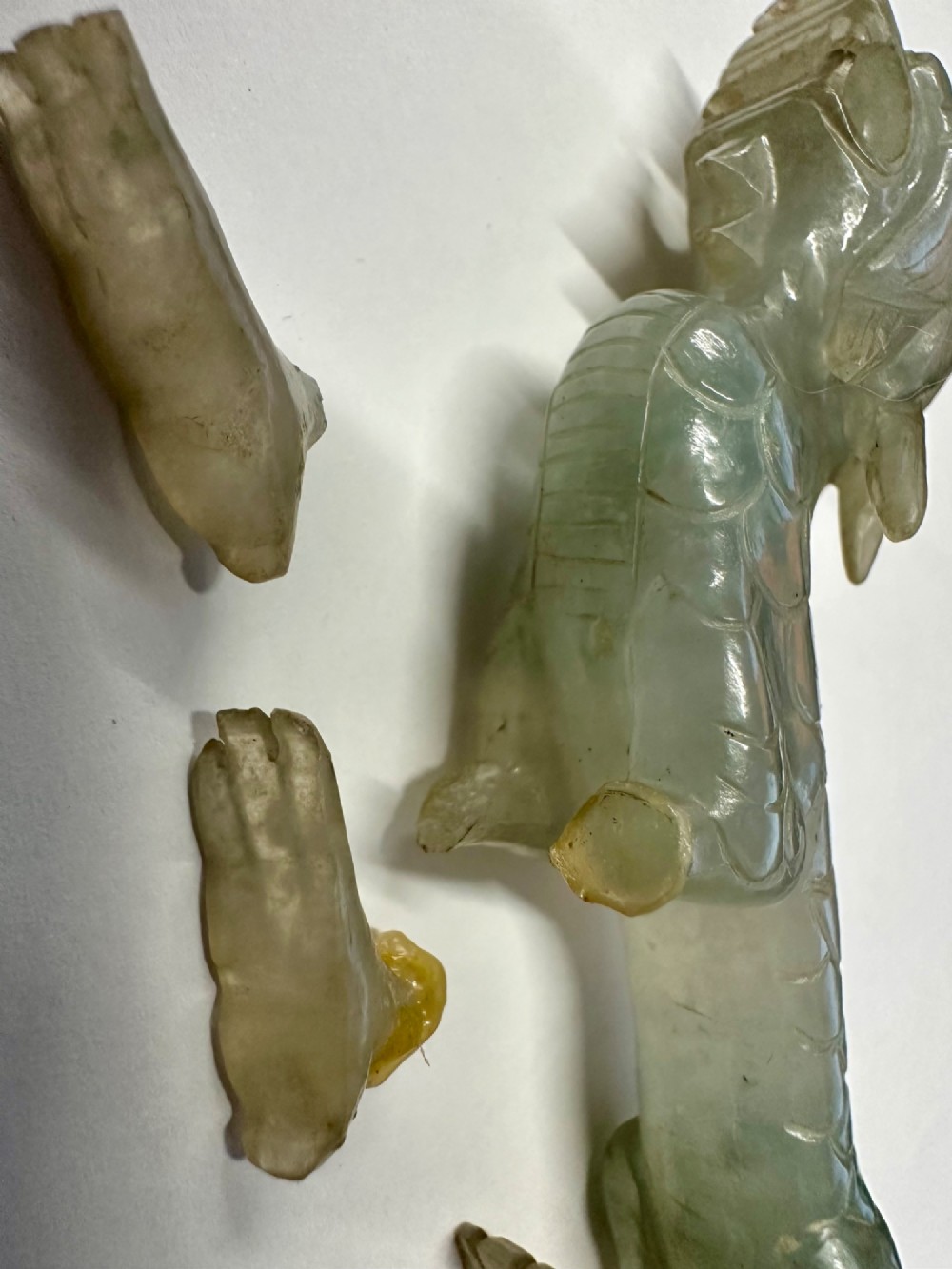 A carved pale green jade dragon sculpture shown alongside a dark pierced hardwood display stand. View VI