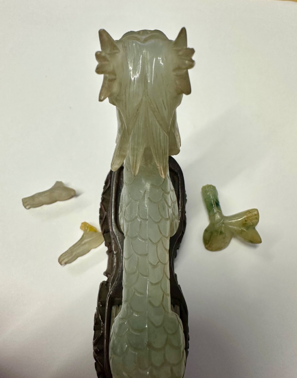 A carved pale green jade dragon sculpture shown alongside a dark pierced hardwood display stand. View IX