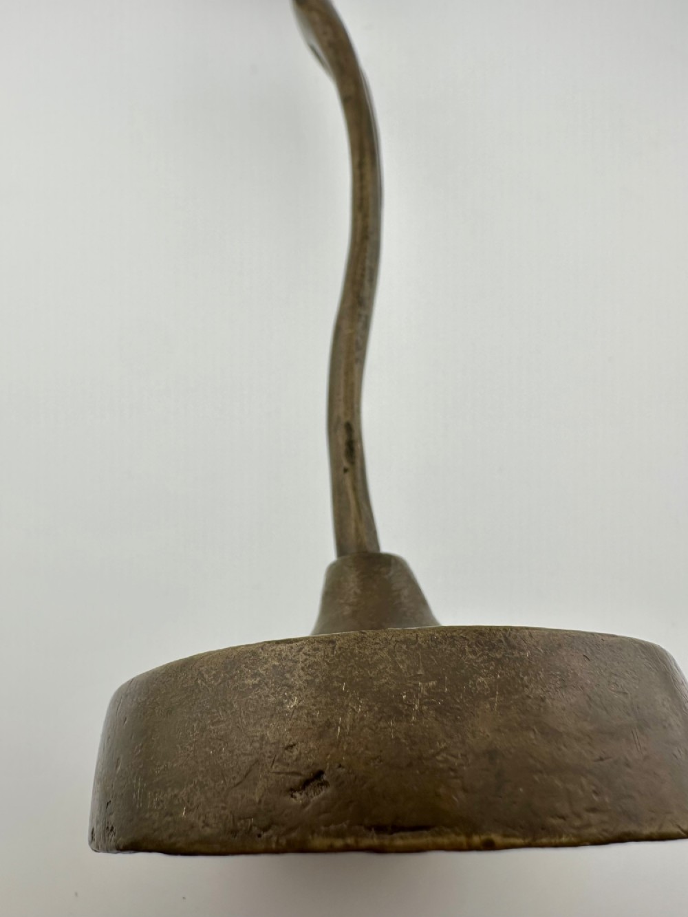A slender modernist bronze sculpture depicting an abstract female dancer with raised arms set upon a round metal base. View V
