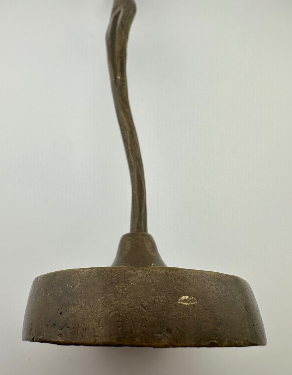 A slender modernist bronze sculpture depicting an abstract female dancer with raised arms set upon a round metal base. View VI