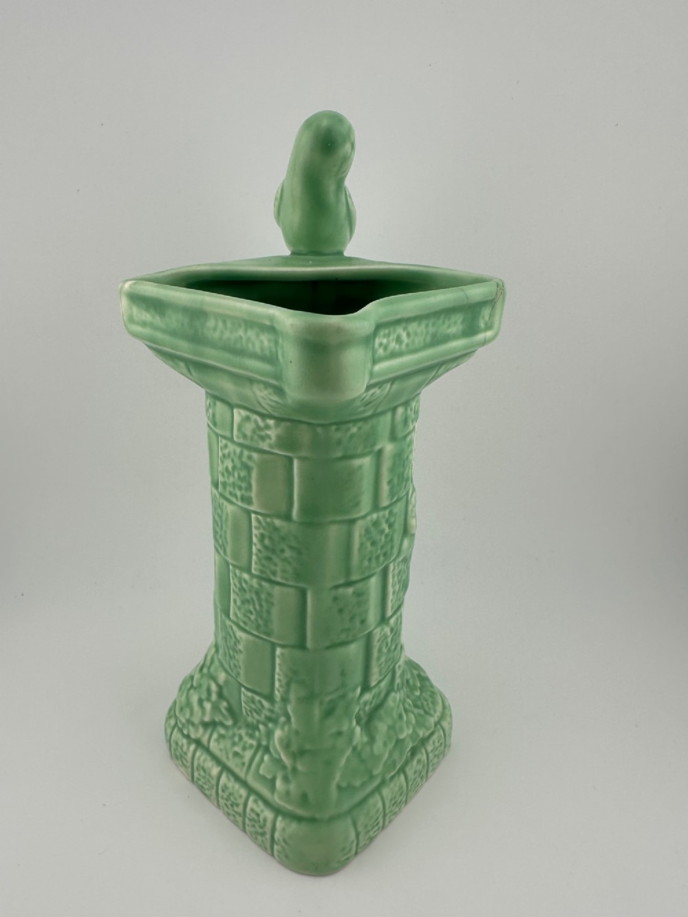 A pale green glazed earthenware Art Deco ceramic jug featuring relief brickwork and a sculpted bird perched on the handle. View II