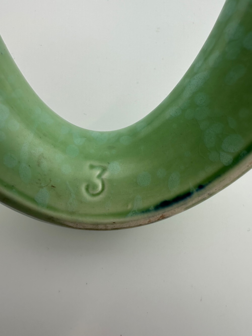 A 1930s oval ceramic posy ring vase with a mottled green glaze, featuring a hollow ring trough designed for short floral stems. View VII