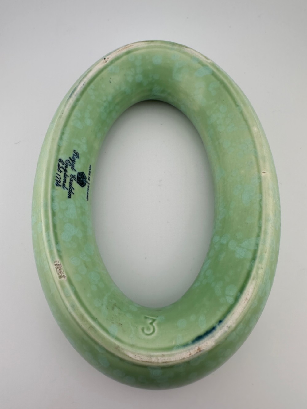 A 1930s oval ceramic posy ring vase with a mottled green glaze, featuring a hollow ring trough designed for short floral stems. View IX