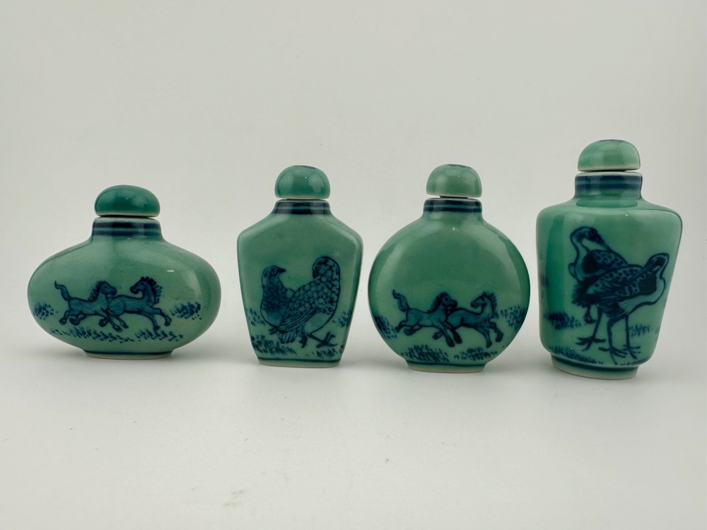 A set of four celadon-green porcelain snuff bottles painted with underglaze blue depictions of horses and birds.