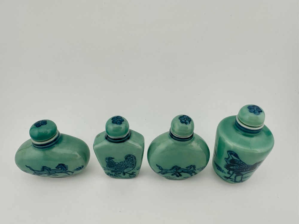 A set of four celadon-green porcelain snuff bottles painted with underglaze blue depictions of horses and birds. View II