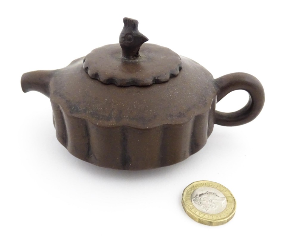A small dark brown unglazed ceramic teapot featuring a lobed body and a bird-shaped finial on the lid. View II