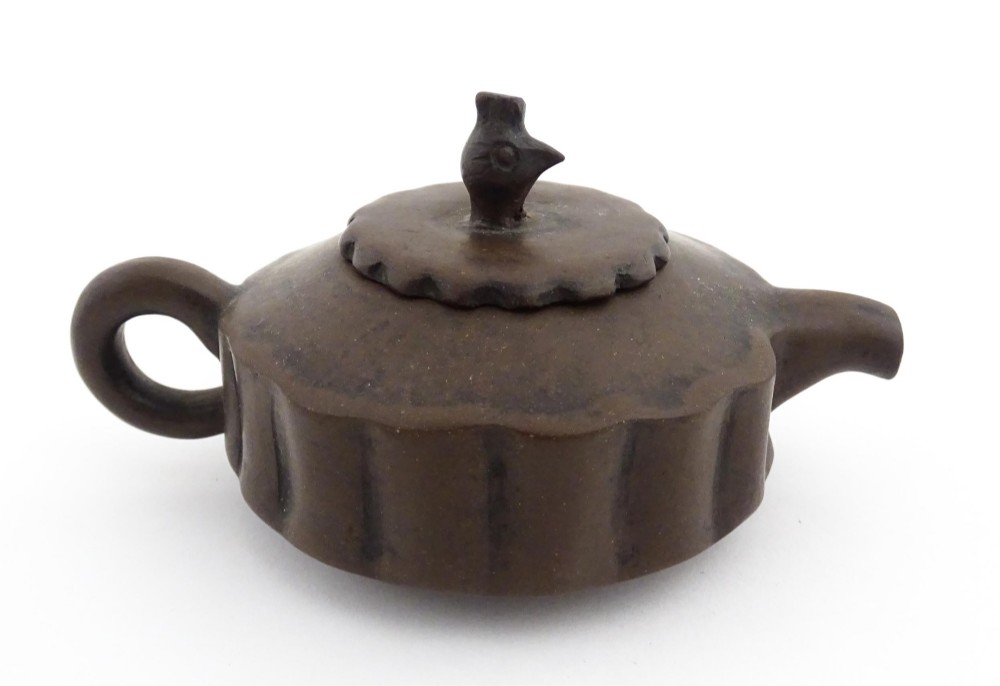 A small dark brown unglazed ceramic teapot featuring a lobed body and a bird-shaped finial on the lid. View X