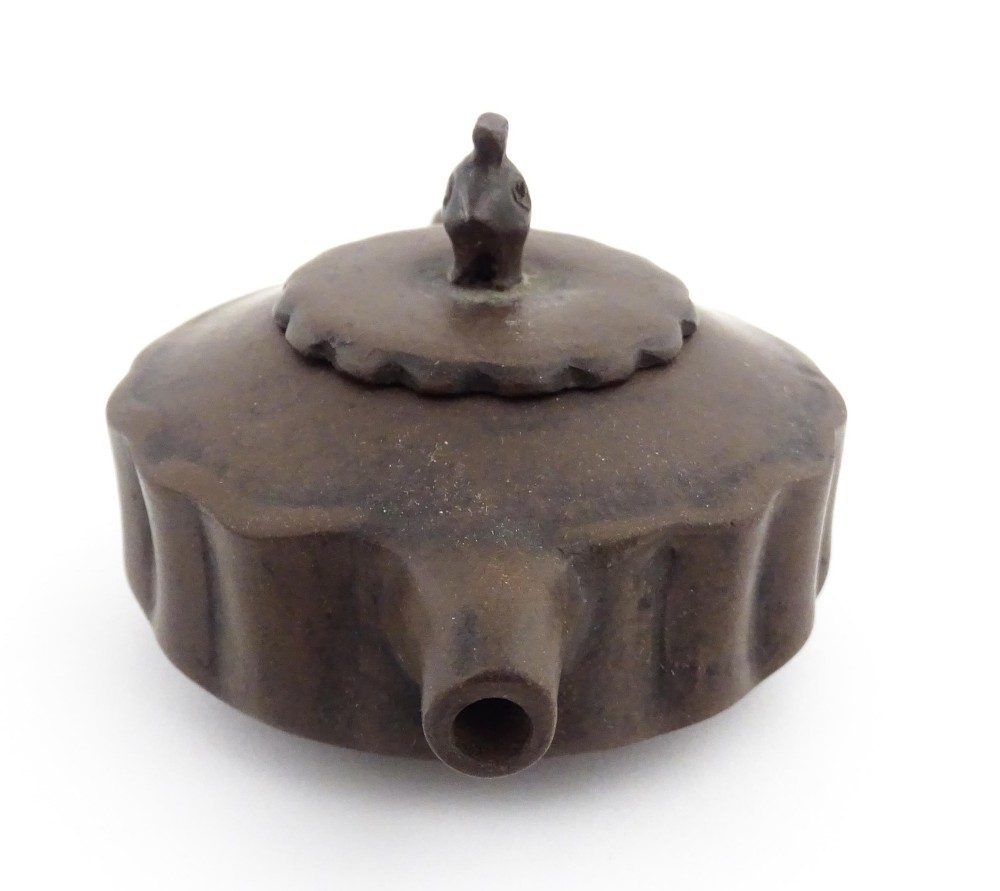 A small dark brown unglazed ceramic teapot featuring a lobed body and a bird-shaped finial on the lid. View XI