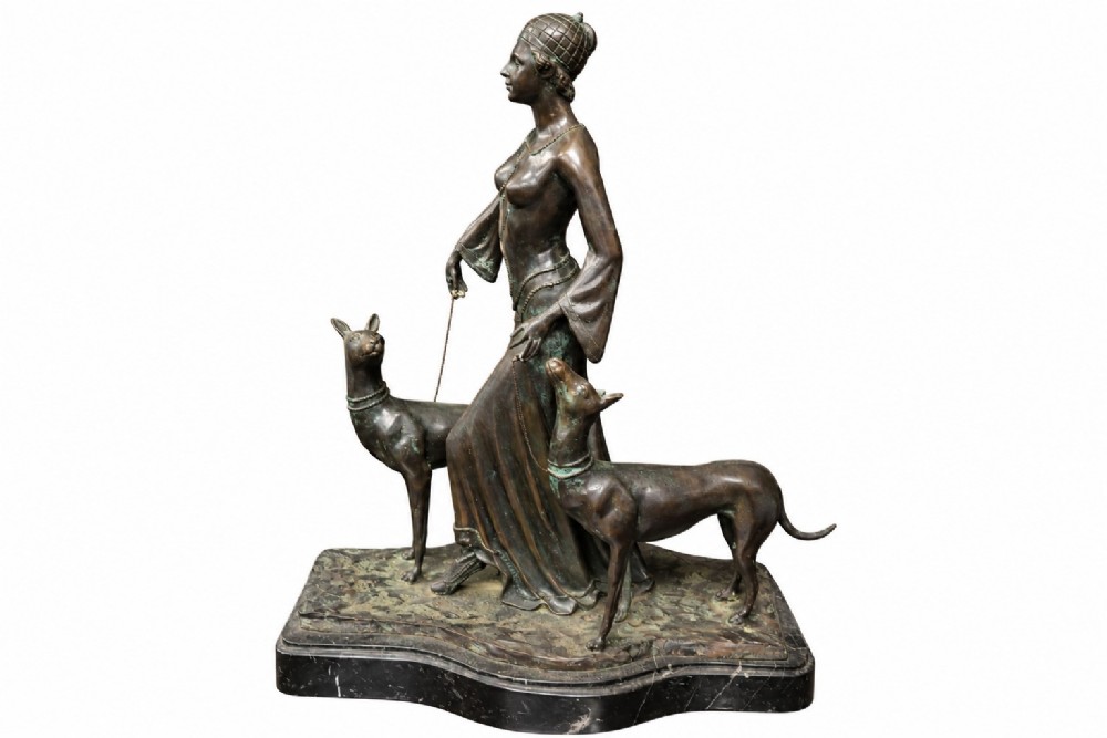 A dark bronze Art Deco sculpture depicting a stylised woman walking two greyhounds on thin chains, set on a dark polished marble base. View II