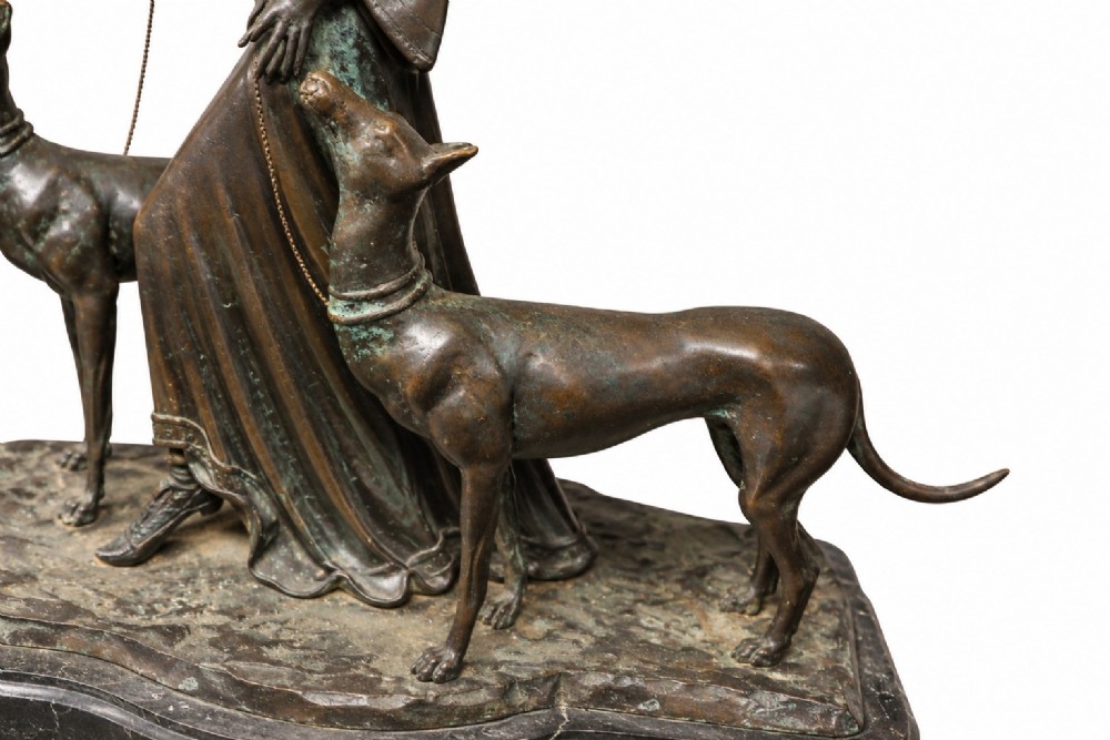 A dark bronze Art Deco sculpture depicting a stylised woman walking two greyhounds on thin chains, set on a dark polished marble base. View III