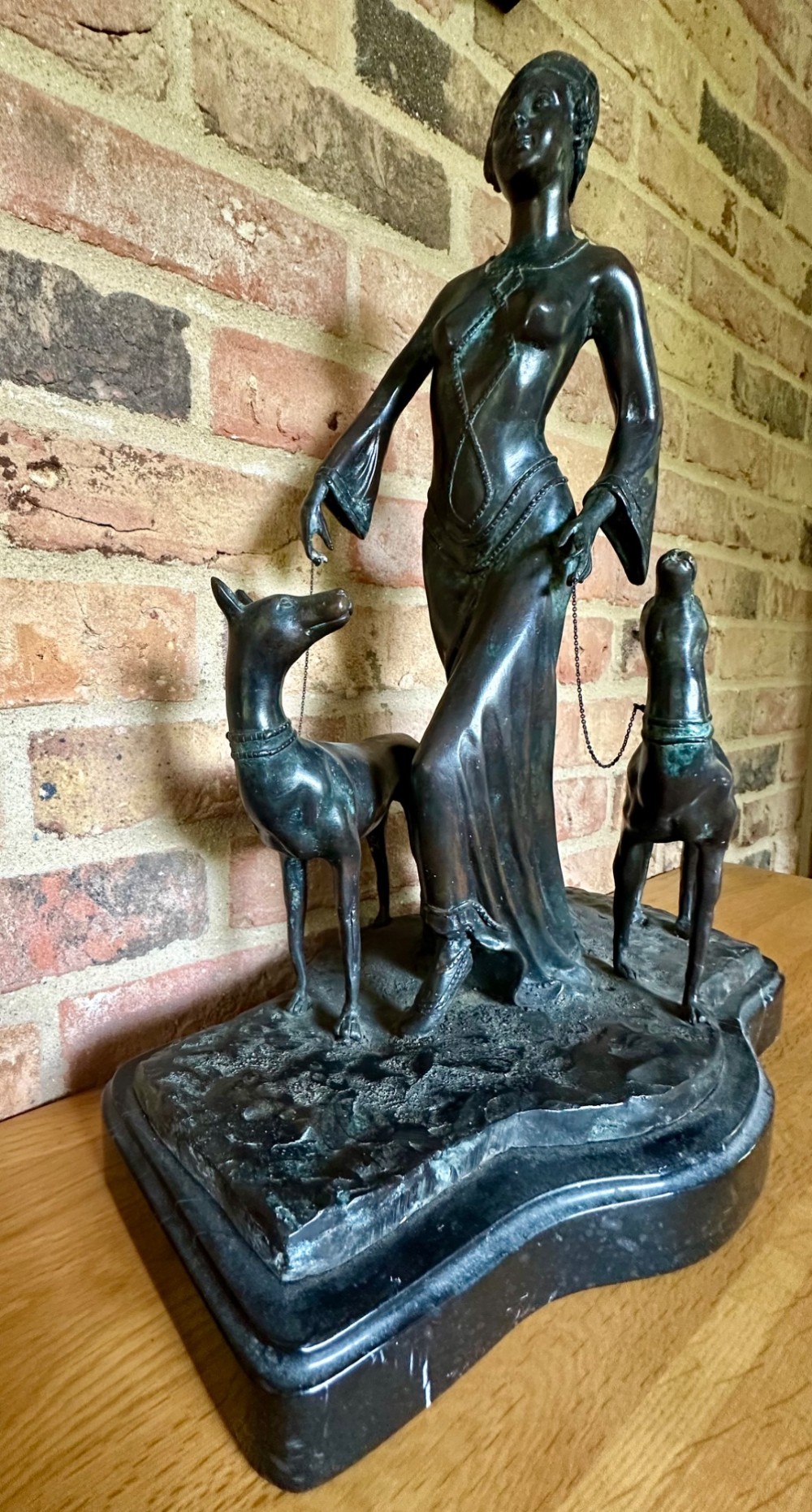 A dark bronze Art Deco sculpture depicting a stylised woman walking two greyhounds on thin chains, set on a dark polished marble base. View VI