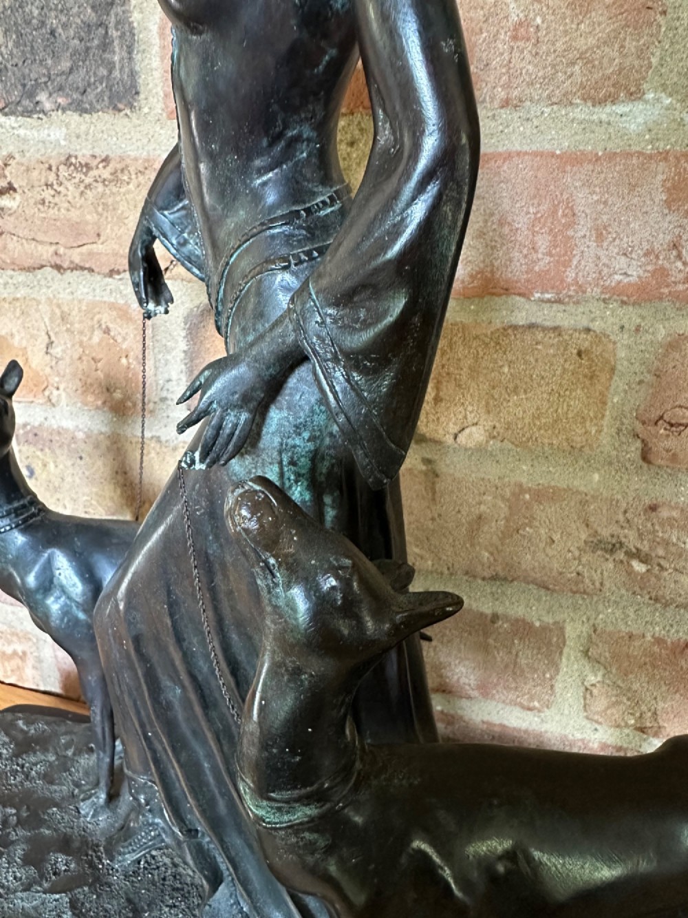 A dark bronze Art Deco sculpture depicting a stylised woman walking two greyhounds on thin chains, set on a dark polished marble base. View VII