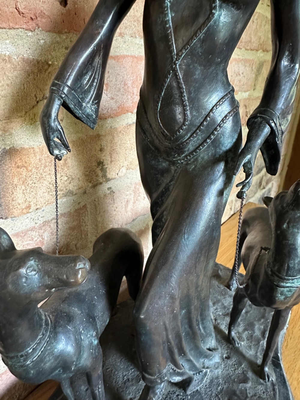 A dark bronze Art Deco sculpture depicting a stylised woman walking two greyhounds on thin chains, set on a dark polished marble base. View IX