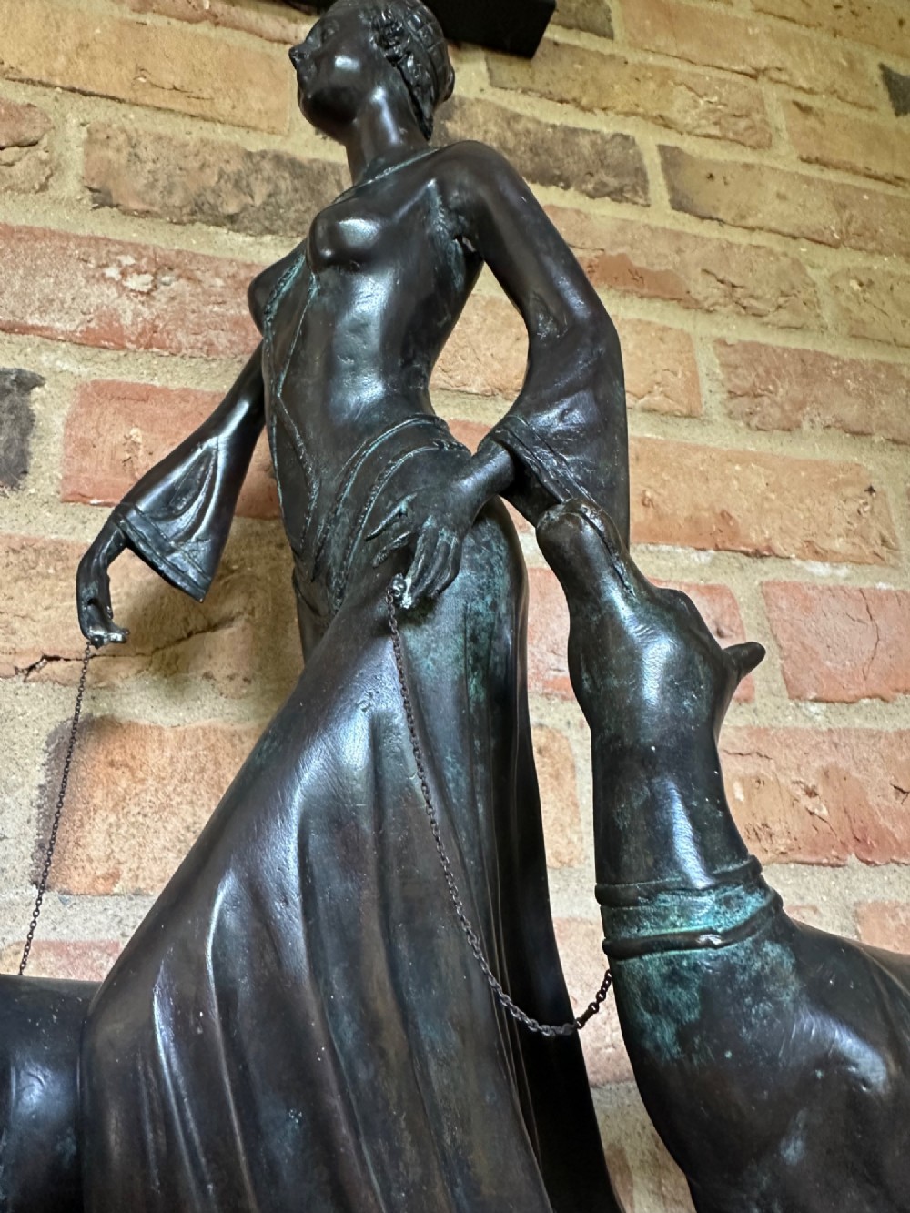 A dark bronze Art Deco sculpture depicting a stylised woman walking two greyhounds on thin chains, set on a dark polished marble base. View XII