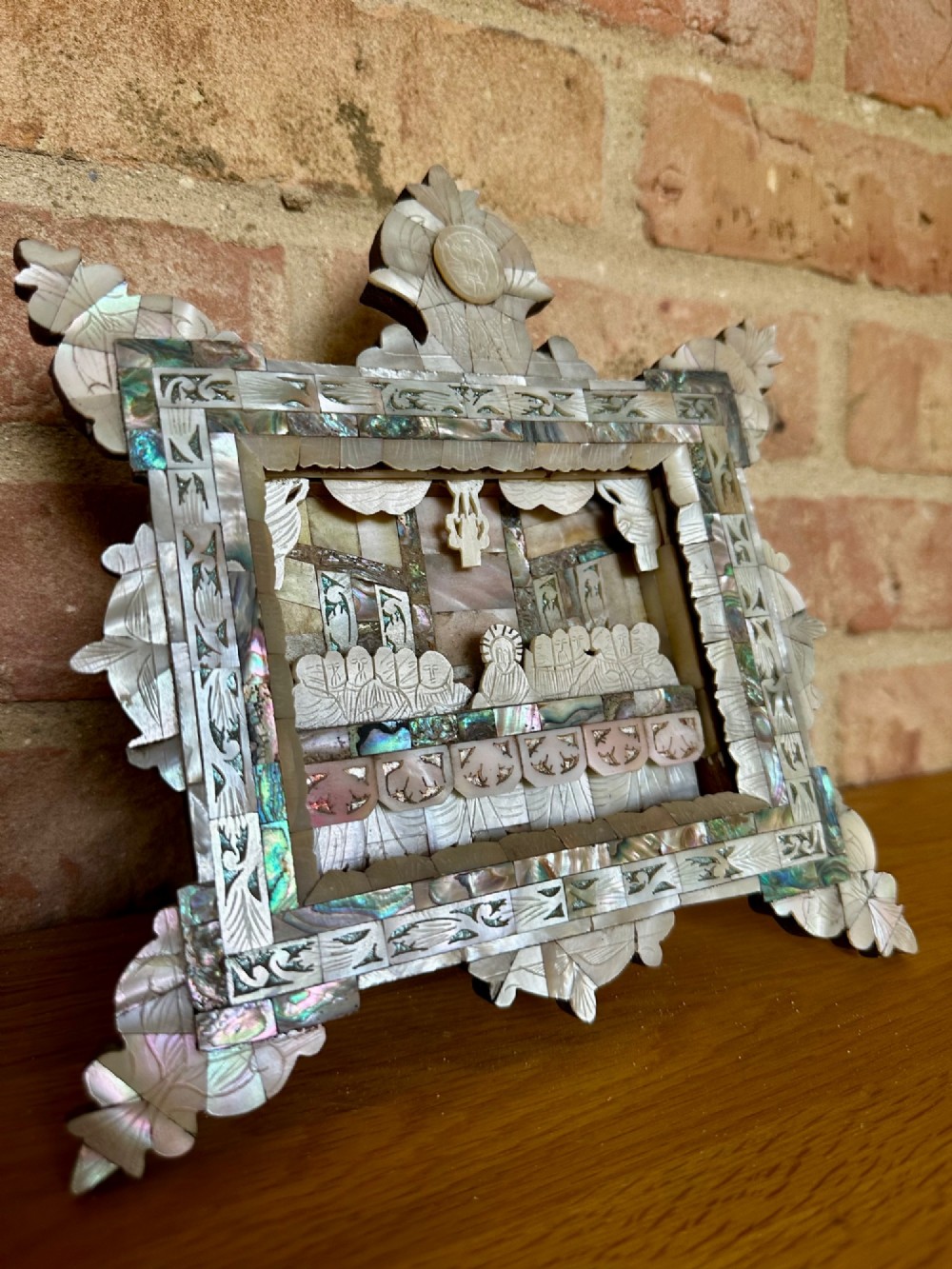 An antique hand-carved mother of pearl and abalone shell diorama frame depicting the Last Supper with elaborate cresting. View III