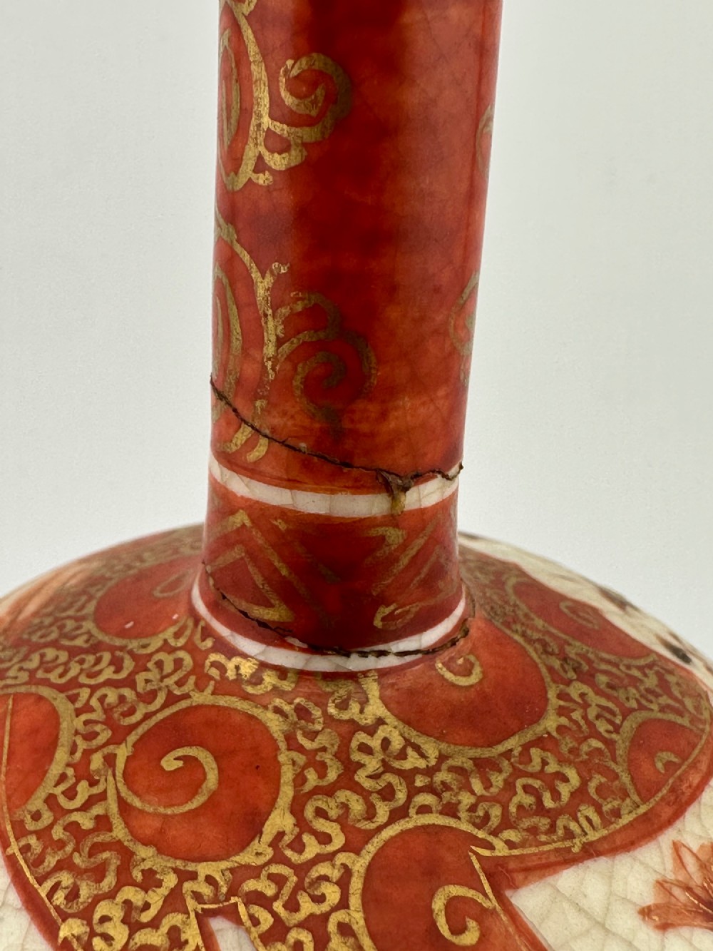 A Japanese Kutani porcelain bottle vase with a tall narrow neck, featuring iron red and gilt floral decoration over a cream crackle glaze body. View IV