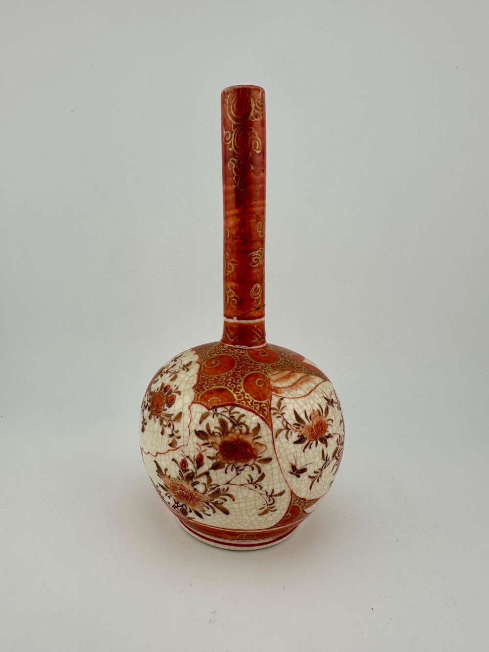 A Japanese Kutani porcelain bottle vase with a tall narrow neck, featuring iron red and gilt floral decoration over a cream crackle glaze body. View VI
