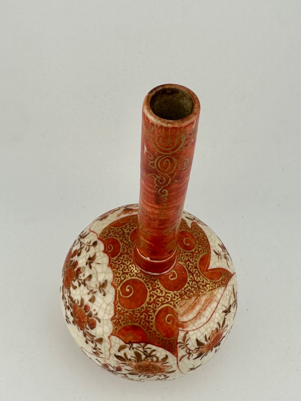 A Japanese Kutani porcelain bottle vase with a tall narrow neck, featuring iron red and gilt floral decoration over a cream crackle glaze body. View VII
