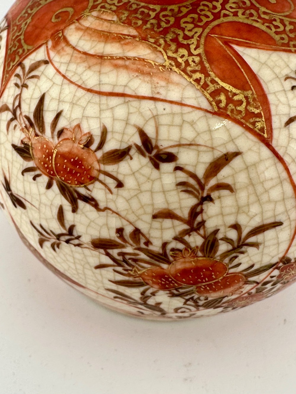 A Japanese Kutani porcelain bottle vase with a tall narrow neck, featuring iron red and gilt floral decoration over a cream crackle glaze body. View XI