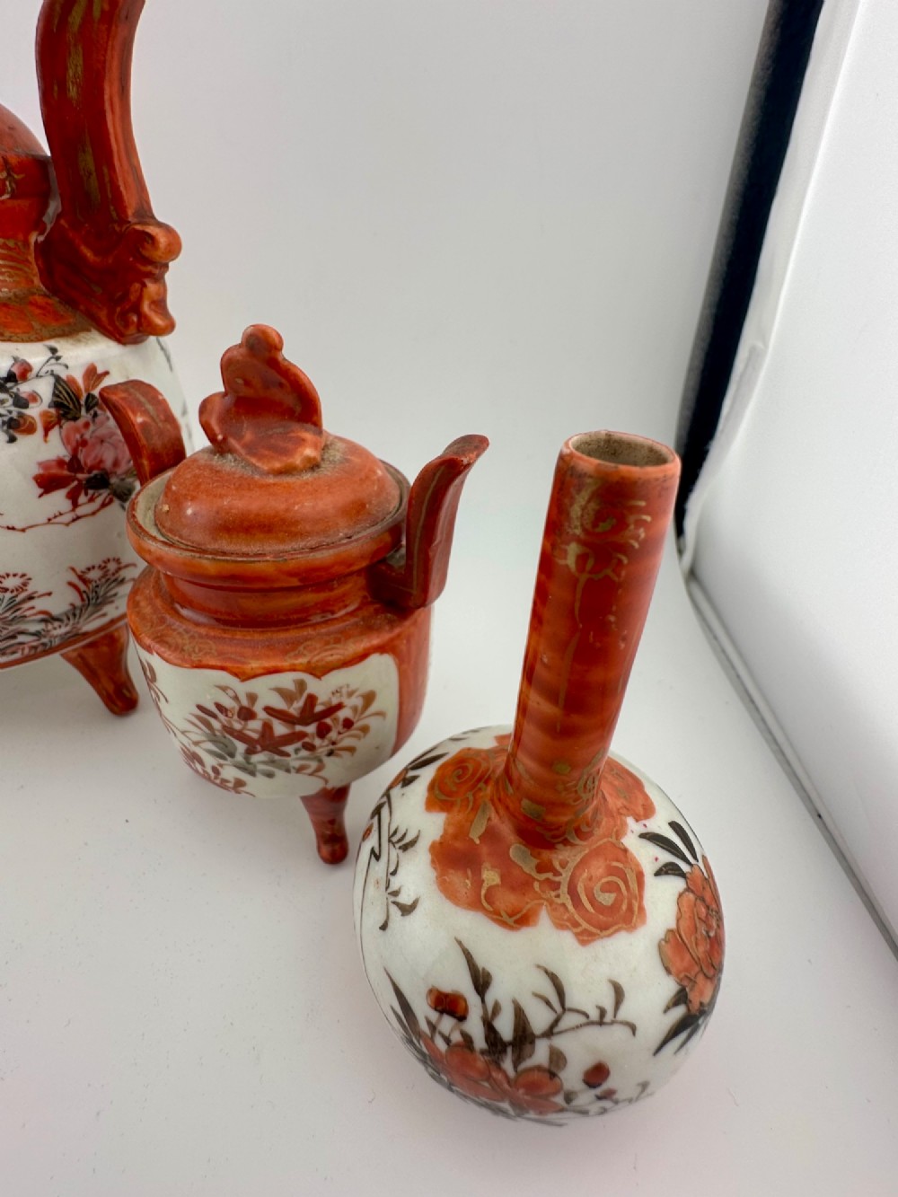 A five-piece Japanese Kutani porcelain garniture set featuring three tripod censers with shishi lion lids and two bottleneck vases in iron-red and polychrome enamel detailing. View III