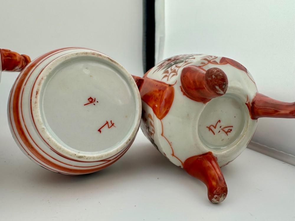 A five-piece Japanese Kutani porcelain garniture set featuring three tripod censers with shishi lion lids and two bottleneck vases in iron-red and polychrome enamel detailing. View X