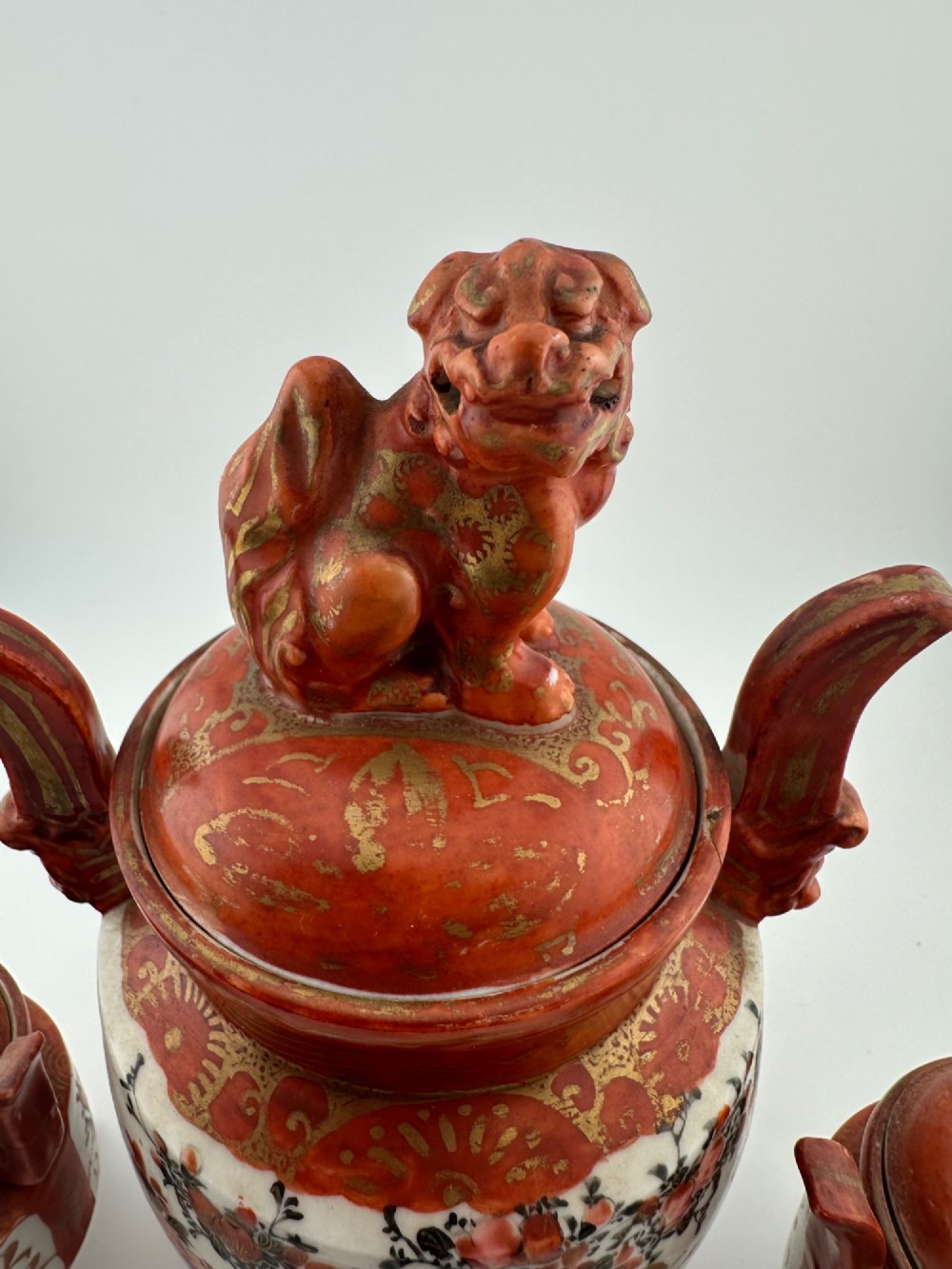 A five-piece Japanese Kutani porcelain garniture set featuring three tripod censers with shishi lion lids and two bottleneck vases in iron-red and polychrome enamel detailing. View XI