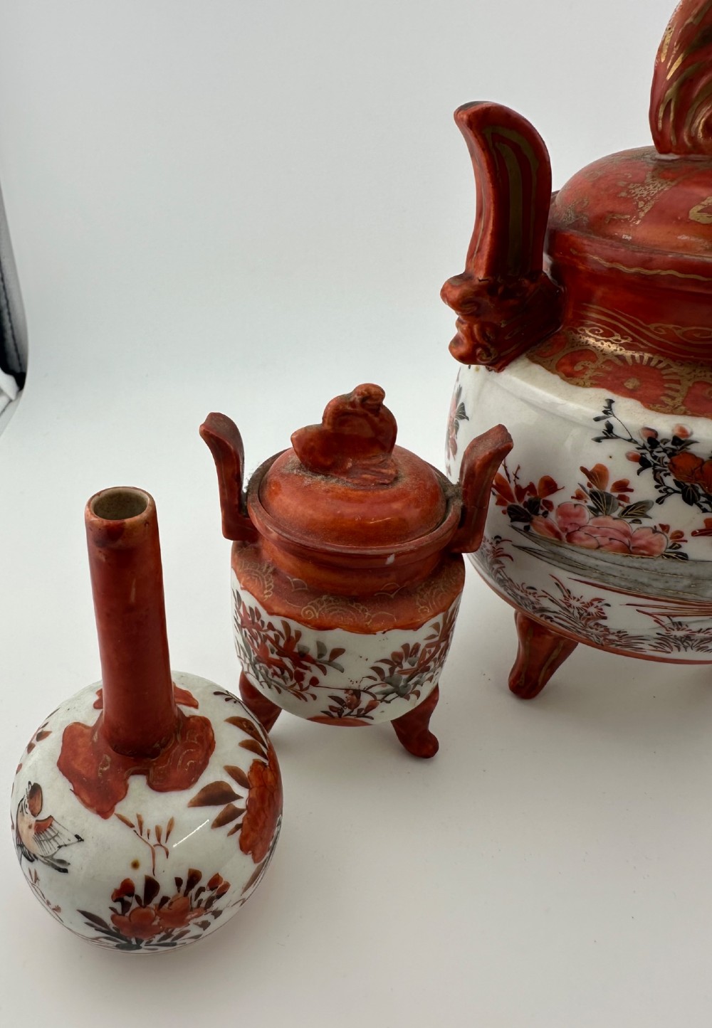A five-piece Japanese Kutani porcelain garniture set featuring three tripod censers with shishi lion lids and two bottleneck vases in iron-red and polychrome enamel detailing. View XII