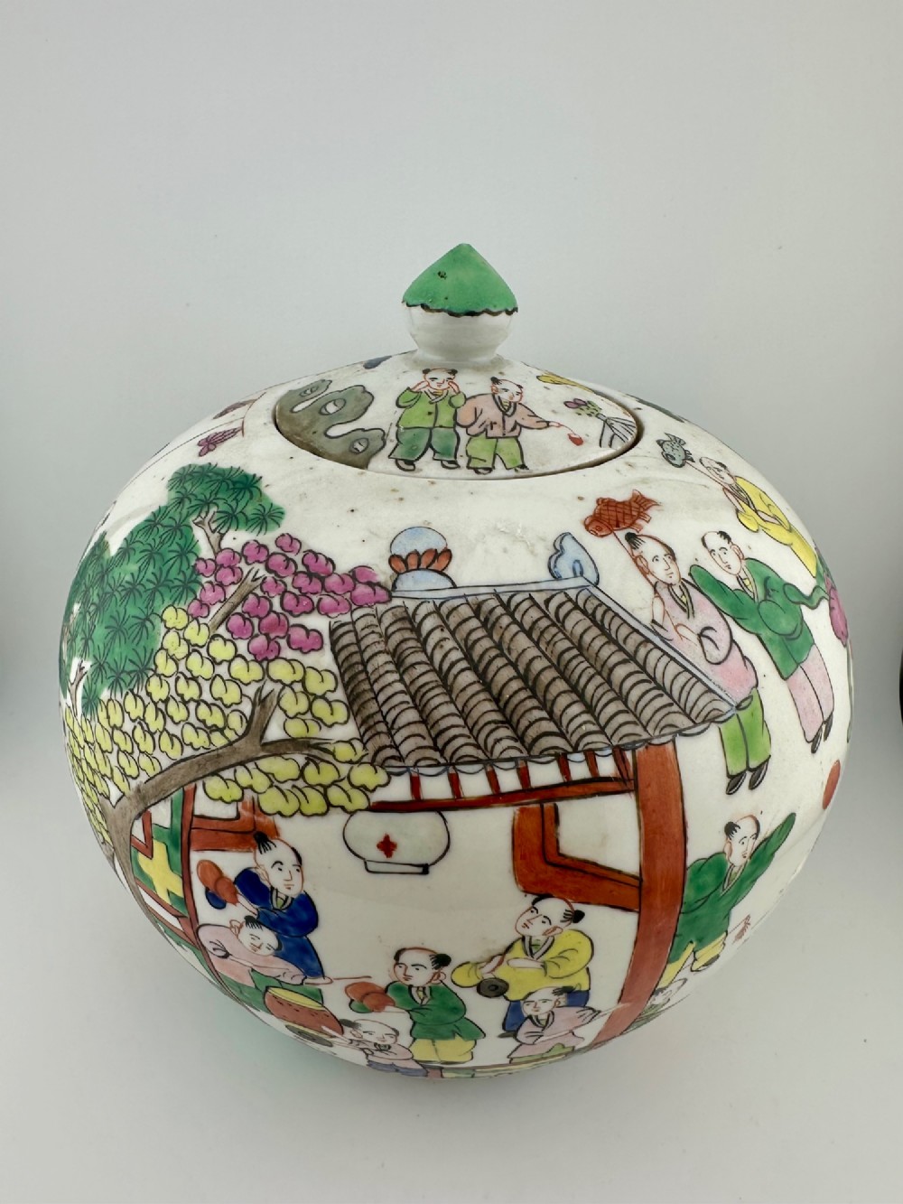 A rounded white porcelain covered jar featuring hand-painted colourful enamels depicting a dragon festival procession with children. View III