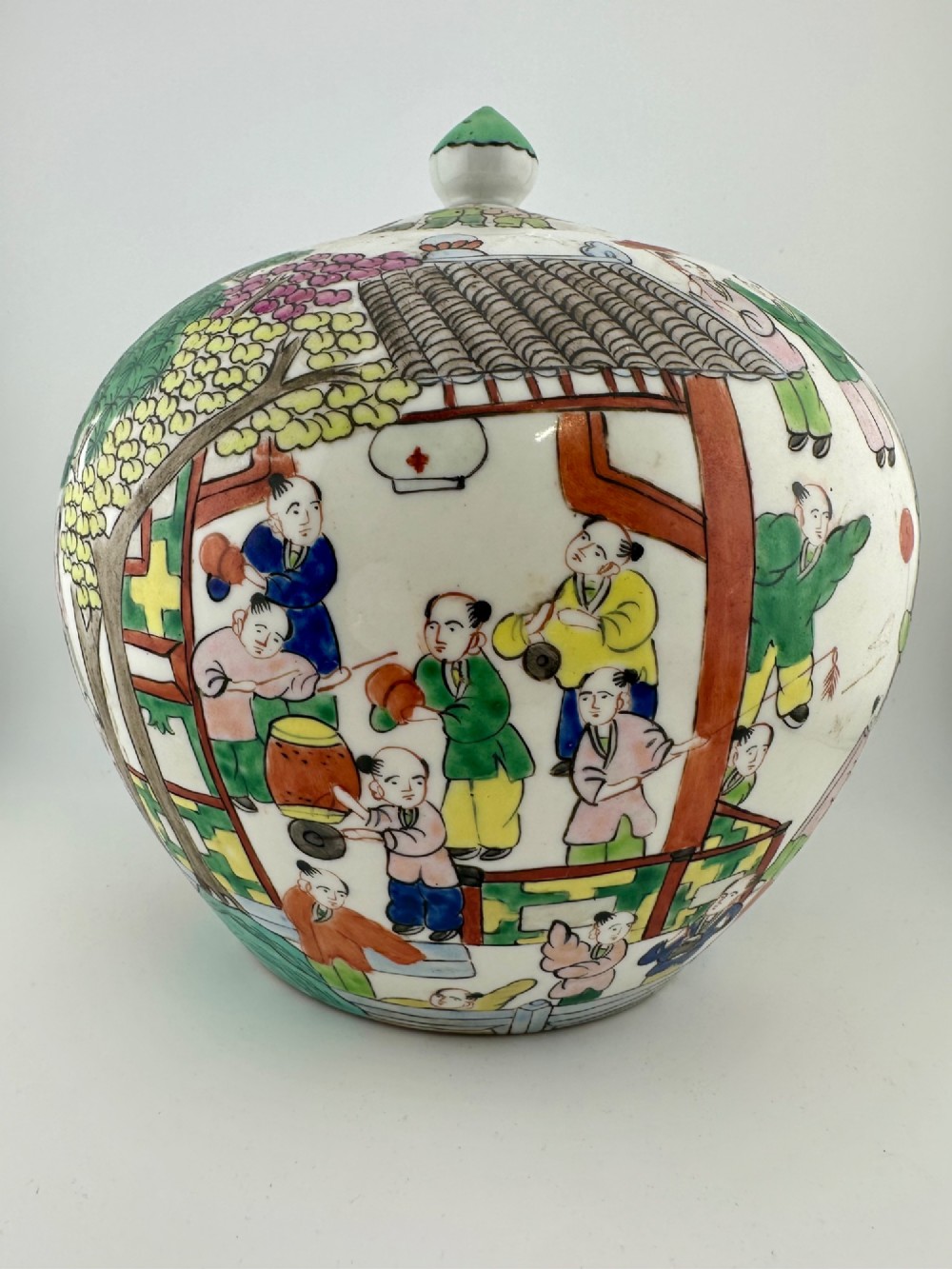 A rounded white porcelain covered jar featuring hand-painted colourful enamels depicting a dragon festival procession with children. View IV