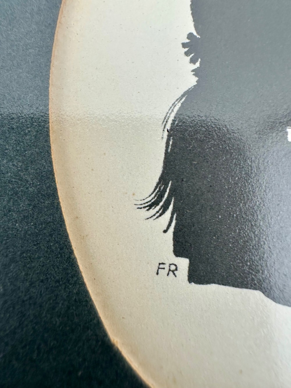 A framed Art Deco silhouette portrait depicting a lady in profile with a decorative hat inside an oval cream mount surrounded by a black and gold frame. View IX