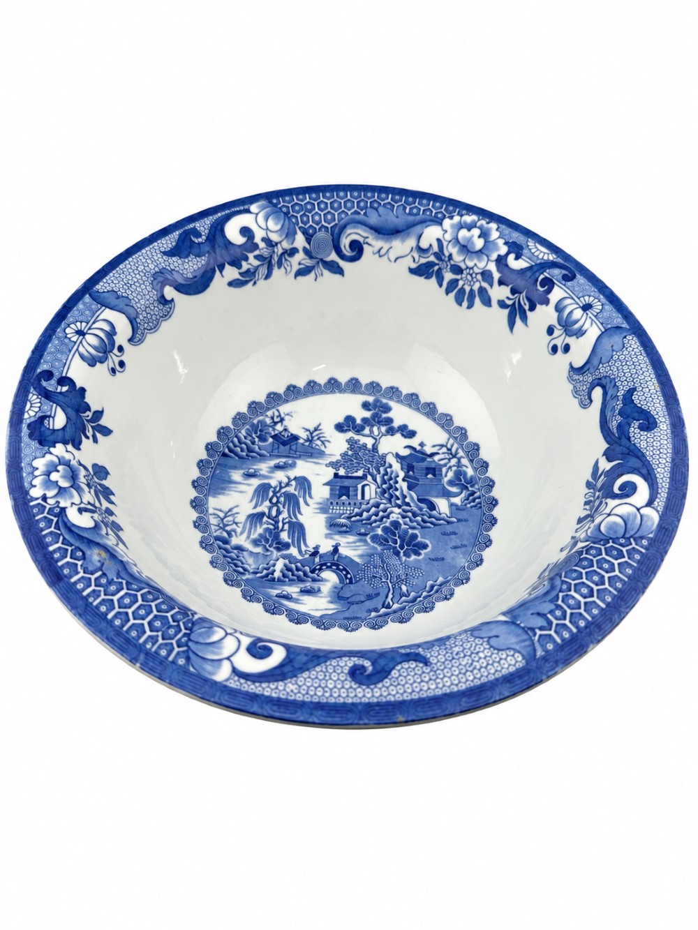 A circular antique blue and white ironstone wash basin bowl featuring a central Chinoiserie landscape scene surrounded by ornate floral and geometric borders.