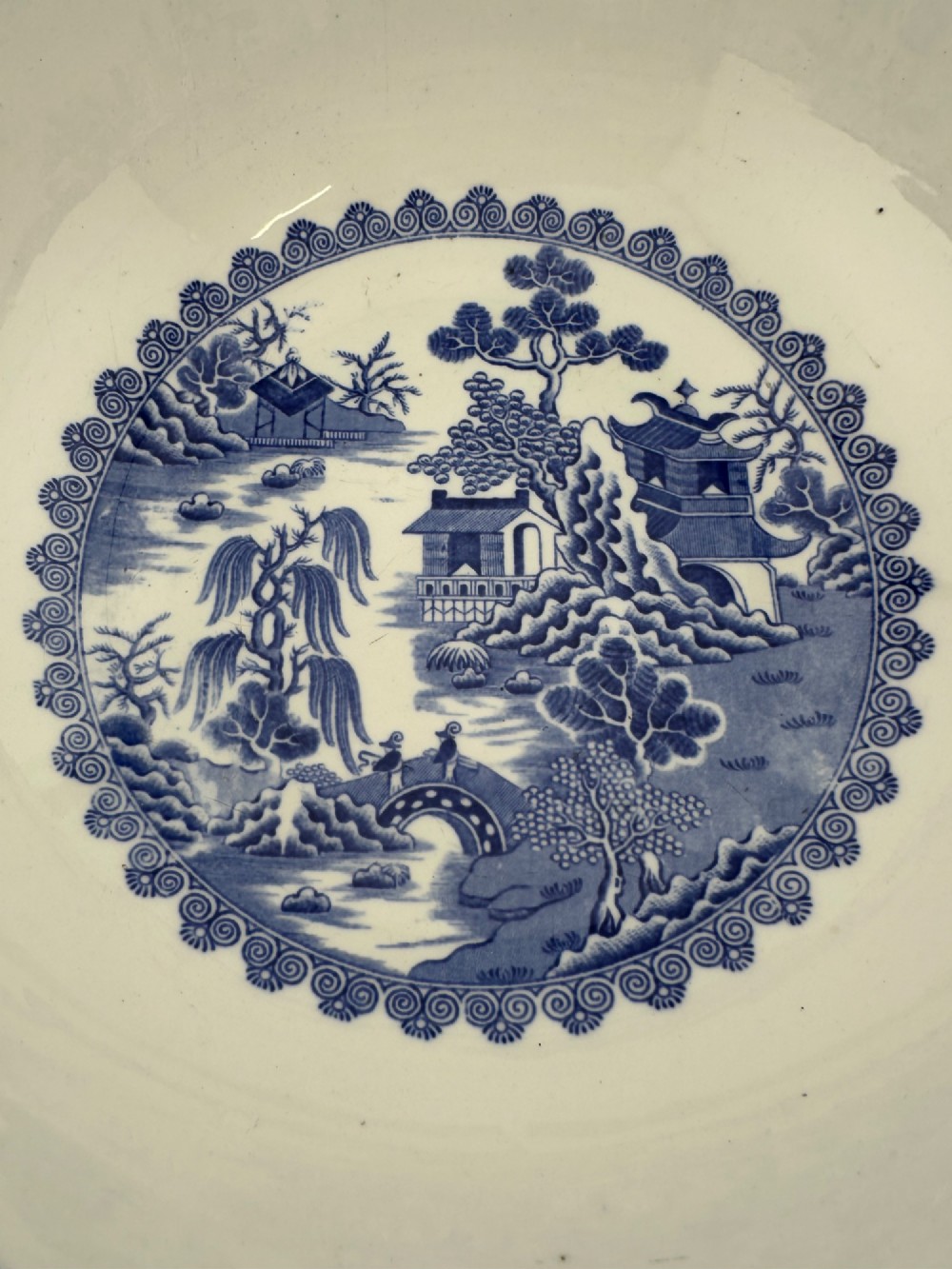 A circular antique blue and white ironstone wash basin bowl featuring a central Chinoiserie landscape scene surrounded by ornate floral and geometric borders. View II