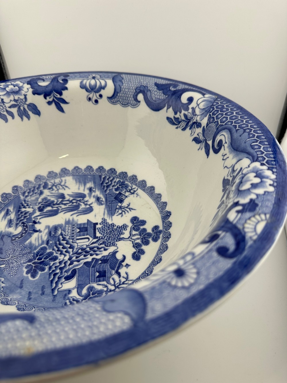 A circular antique blue and white ironstone wash basin bowl featuring a central Chinoiserie landscape scene surrounded by ornate floral and geometric borders. View III