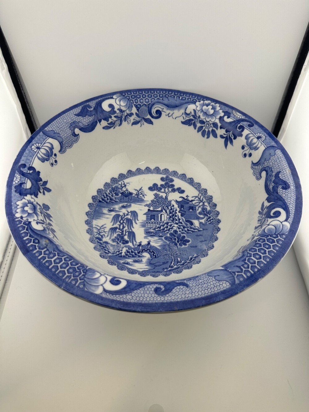 A circular antique blue and white ironstone wash basin bowl featuring a central Chinoiserie landscape scene surrounded by ornate floral and geometric borders. View XIII