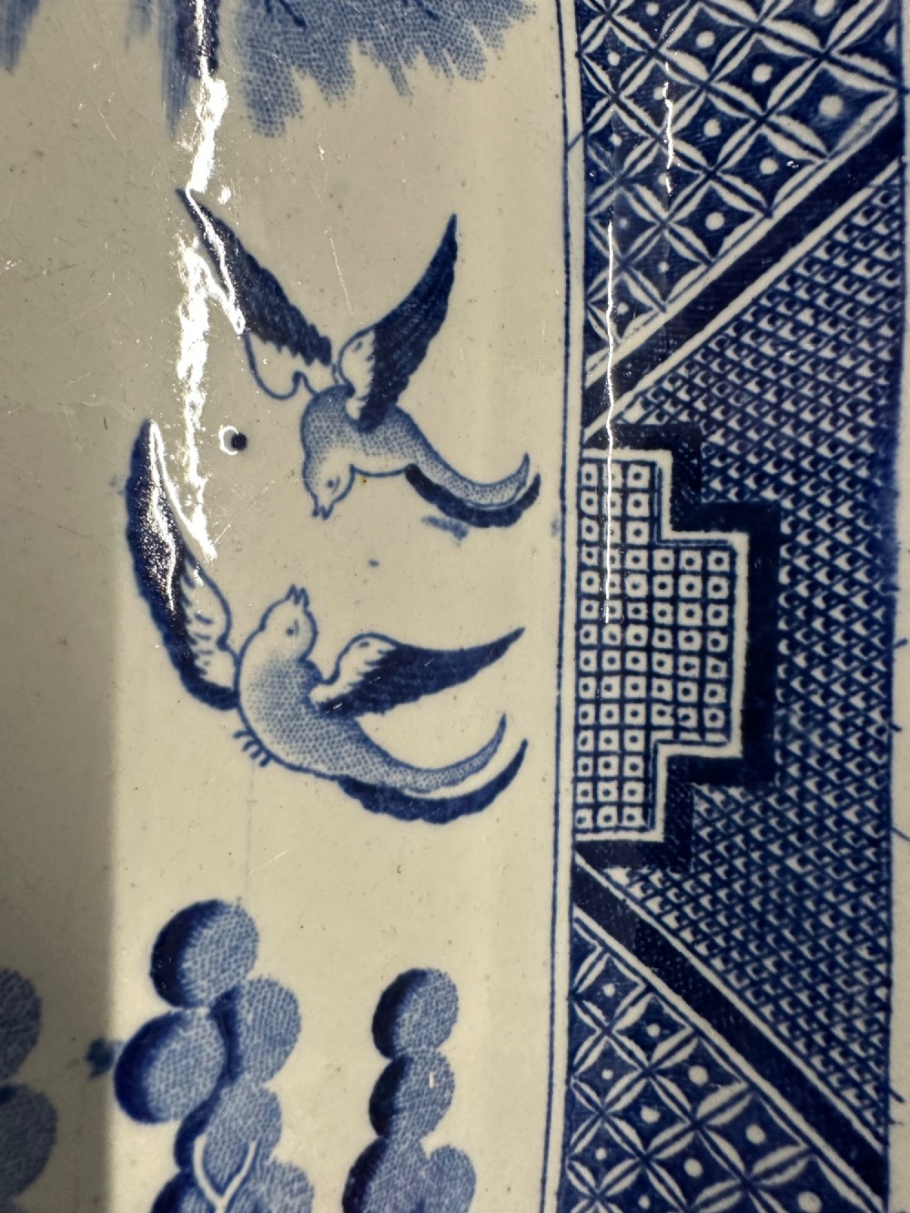 An oval early Victorian Staffordshire earthenware meat platter featuring a cobalt blue and white transferware Willow pattern with pagodas, birds, and a decorative geometric border. View III