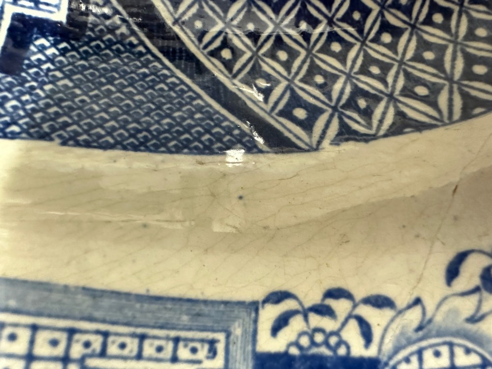 An oval early Victorian Staffordshire earthenware meat platter featuring a cobalt blue and white transferware Willow pattern with pagodas, birds, and a decorative geometric border. View V
