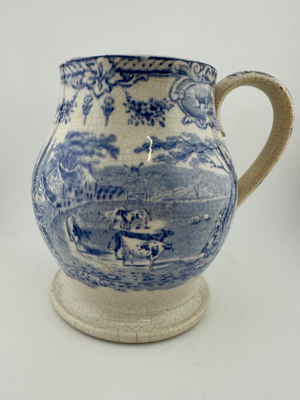 An early Victorian blue and white transferware ceramic jug featuring a pastoral cattle scene with fine glaze crazing throughout. View II