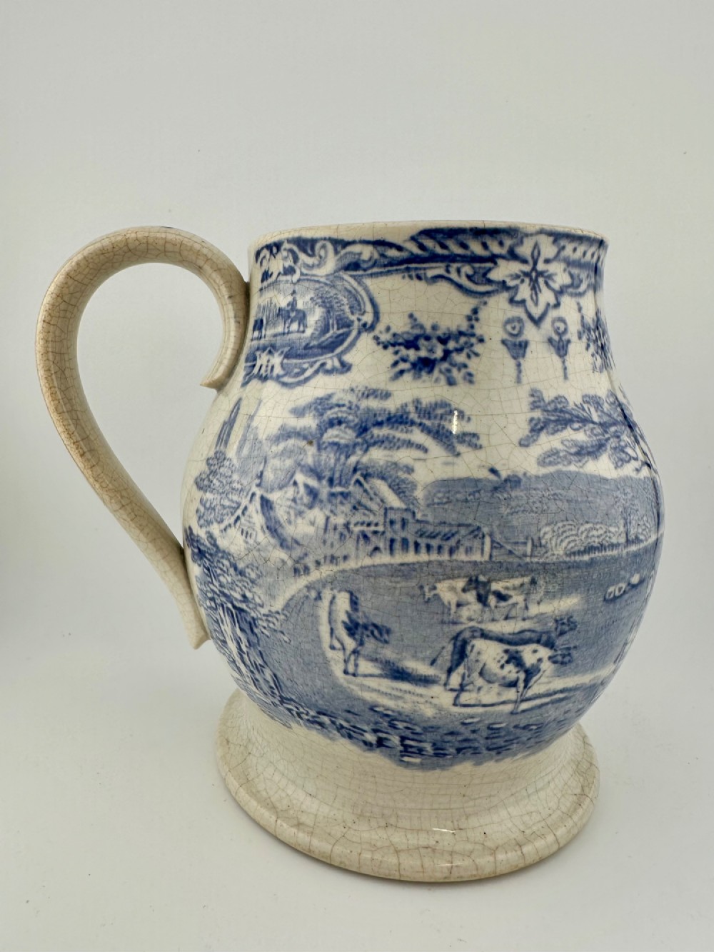 An early Victorian blue and white transferware ceramic jug featuring a pastoral cattle scene with fine glaze crazing throughout. View IV