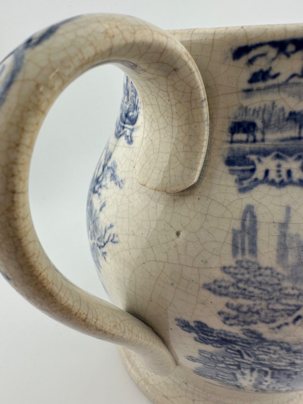 An early Victorian blue and white transferware ceramic jug featuring a pastoral cattle scene with fine glaze crazing throughout. View IX