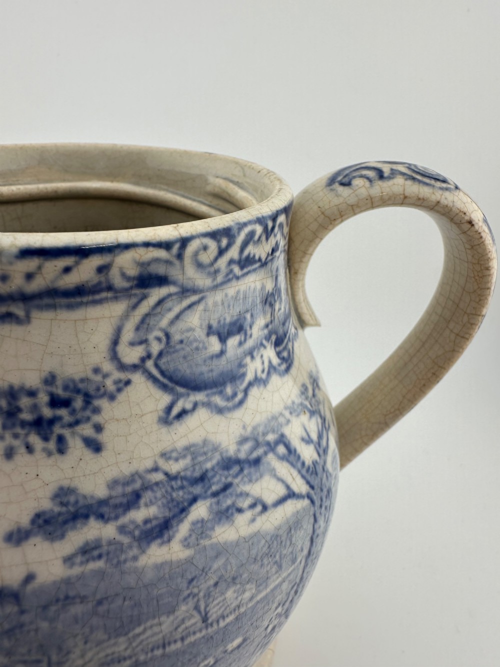An early Victorian blue and white transferware ceramic jug featuring a pastoral cattle scene with fine glaze crazing throughout. View XIV