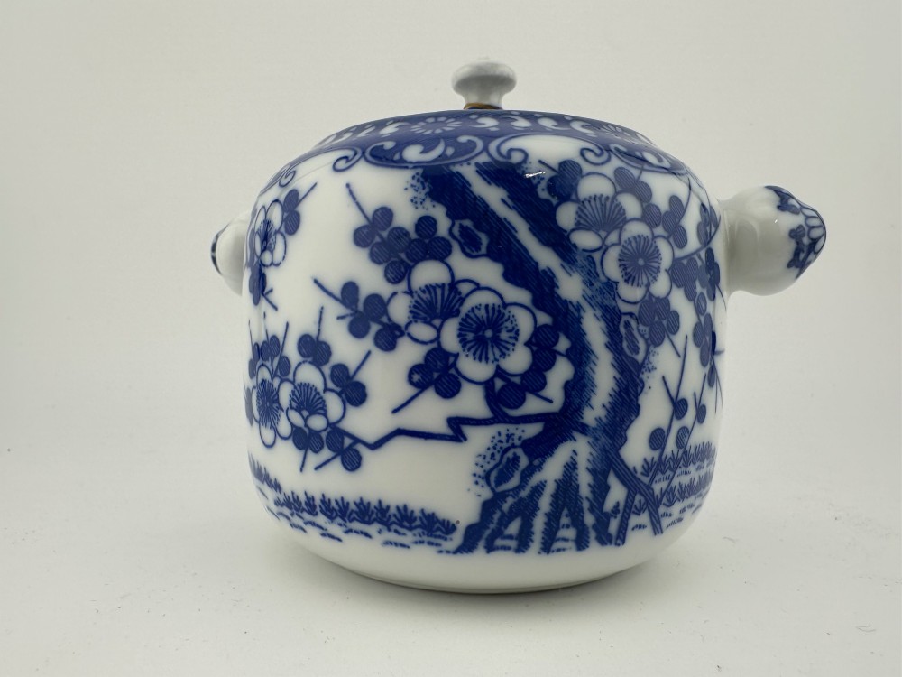 A Japanese Meiji period blue and white porcelain incense burner decorated with hand-painted prunus branches, featuring a fitted lid and side lugs. View II