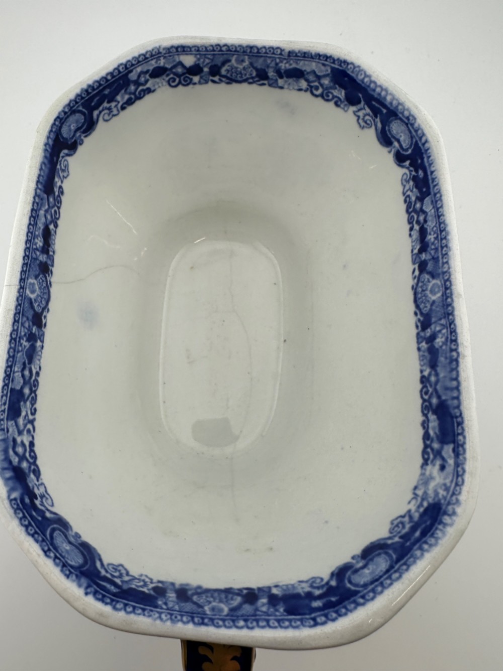 An antique oval ironstone jardiniere featuring blue and white transfer-printed Chinoiserie landscape decoration and small side handles with gilded detailing. View IV
